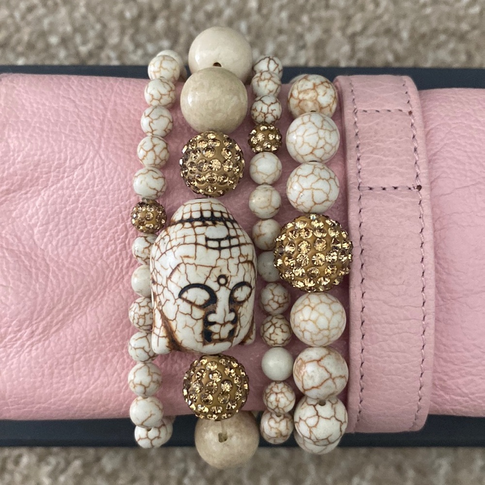Set of four stackable bracelets, cream with gold accents.